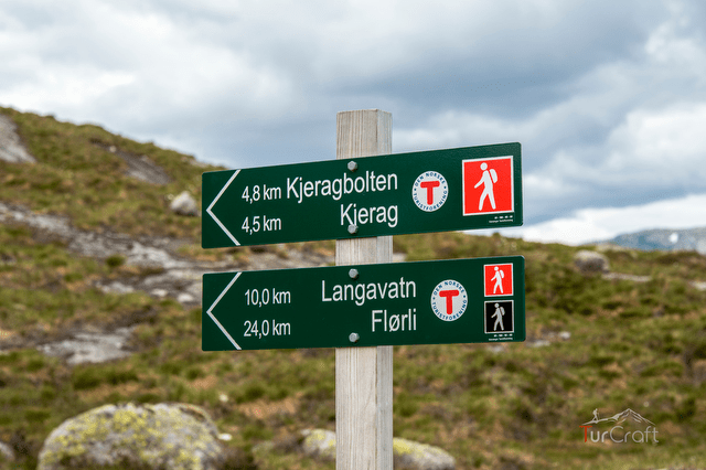 Hikers walking across pale rock slabs on the Kjerag trail above Lysefjord